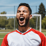 Soccer player cheering enthusiastically on the field.
