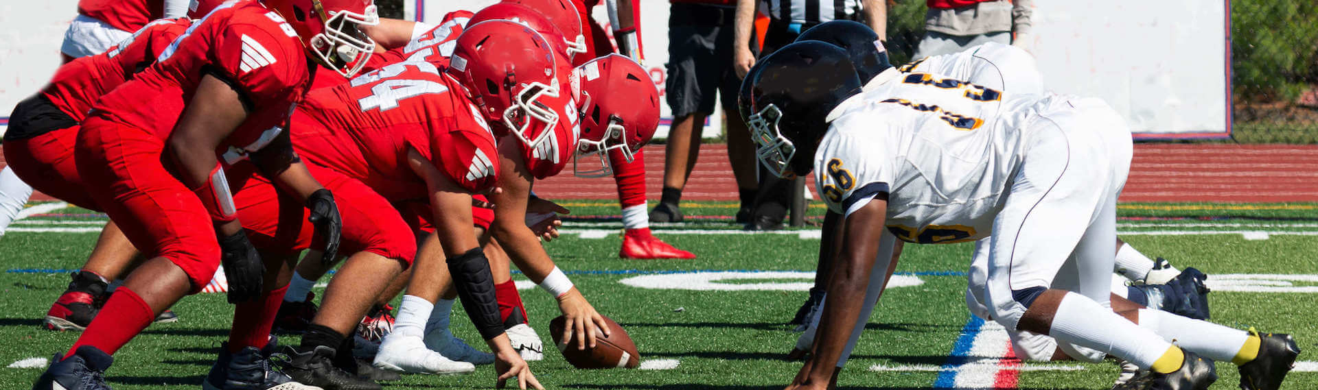 Two football teams in red and white jerseys respectively, taking position in a game