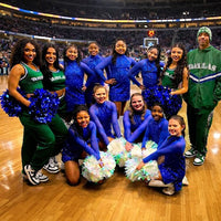 Cheerleaders wearing blue and green uniforms holding metallic and iridescent pom poms on a basketball court.